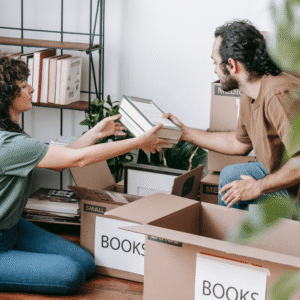 Woman and man decluttering books from a sheft.