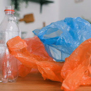 A blue and orange plastic bag along with a empty plastic bottle.