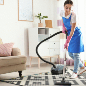 A woman in a blue apron   vacuuming a rug.