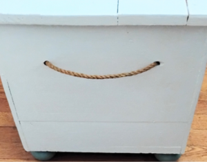 Rope handles on a white trunk.
