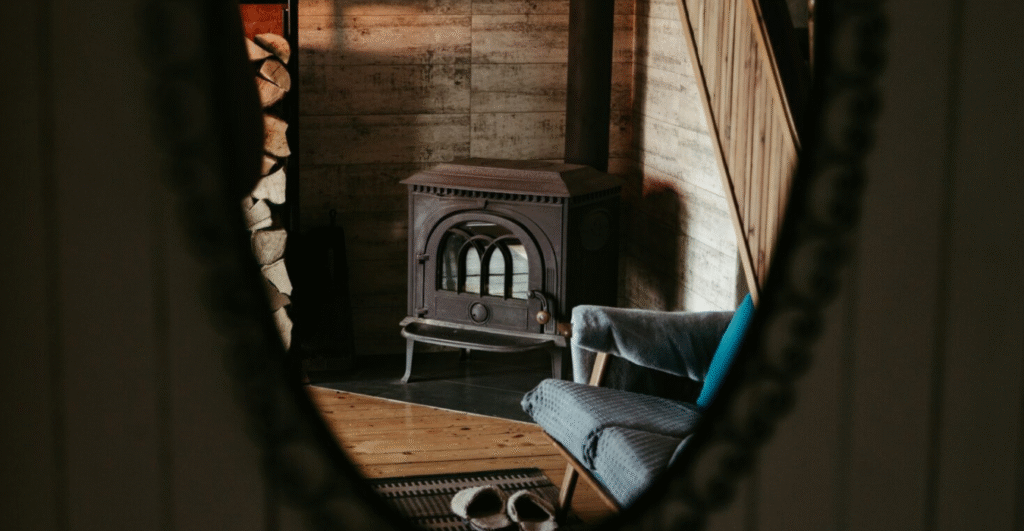 a wood burning stove against a wood wall an a chair in the room