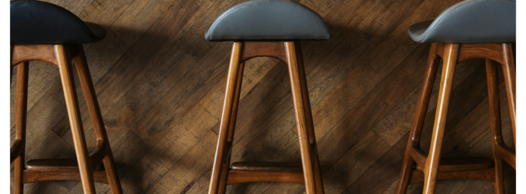 Three bar stool with blue seat and wood legs.